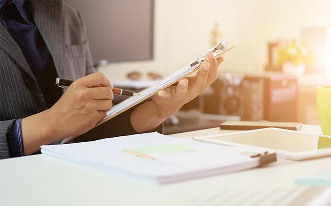 Person writing on their tablet at a desk